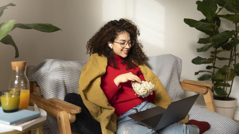 Девушка в приятной атмосфере смотрит сериал на ноутбуке