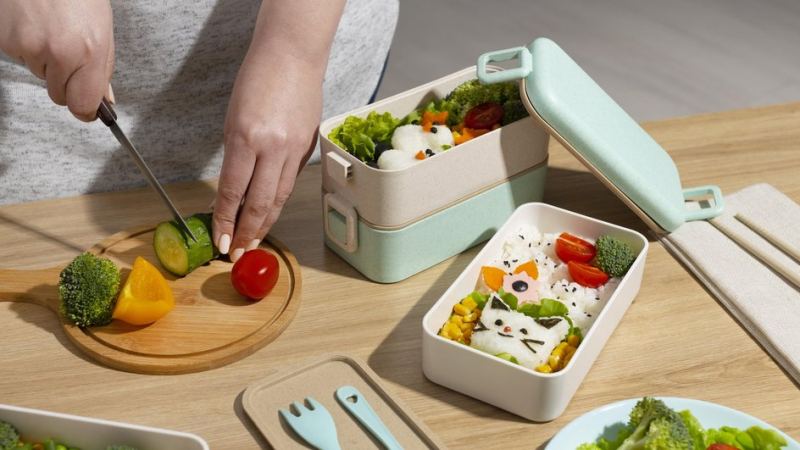 Женщина режет овощи и кладет их в ланч-бокс