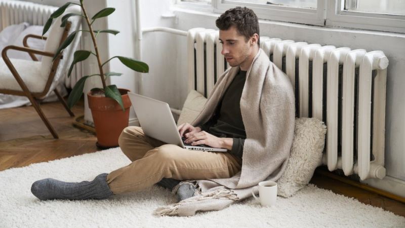 Мужчина с ноутбуков возле батареи с отключенным отоплением в Москве