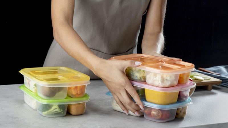 Девушка убирает контейнеры с едой со стола