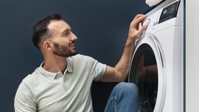 Мужчина включает стиральную машину для очистки от накипи